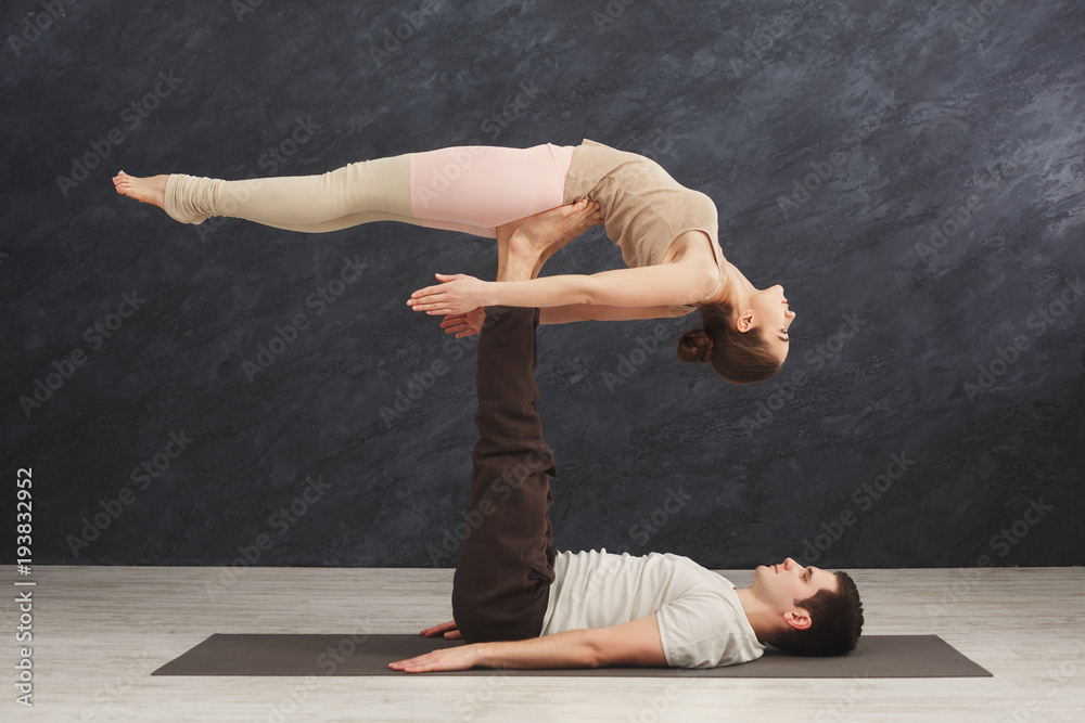 Young couple practicing acroyoga on mat together