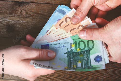Foto Hands transferring money on wooden background