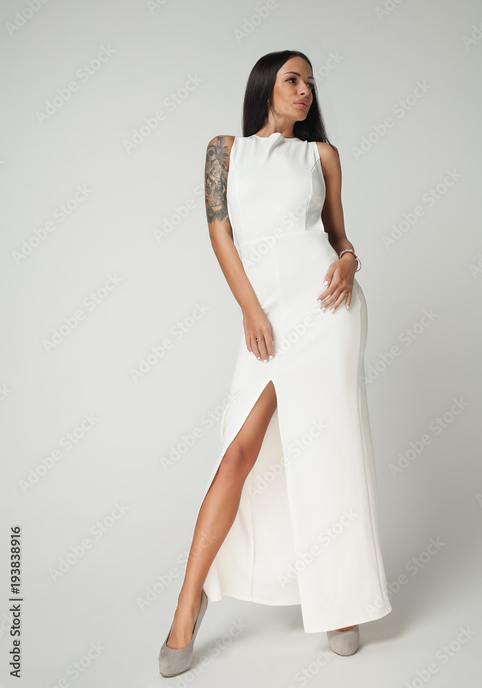 Young beautiful female model in white dress on grey background Young beautiful female model in white dress on grey background