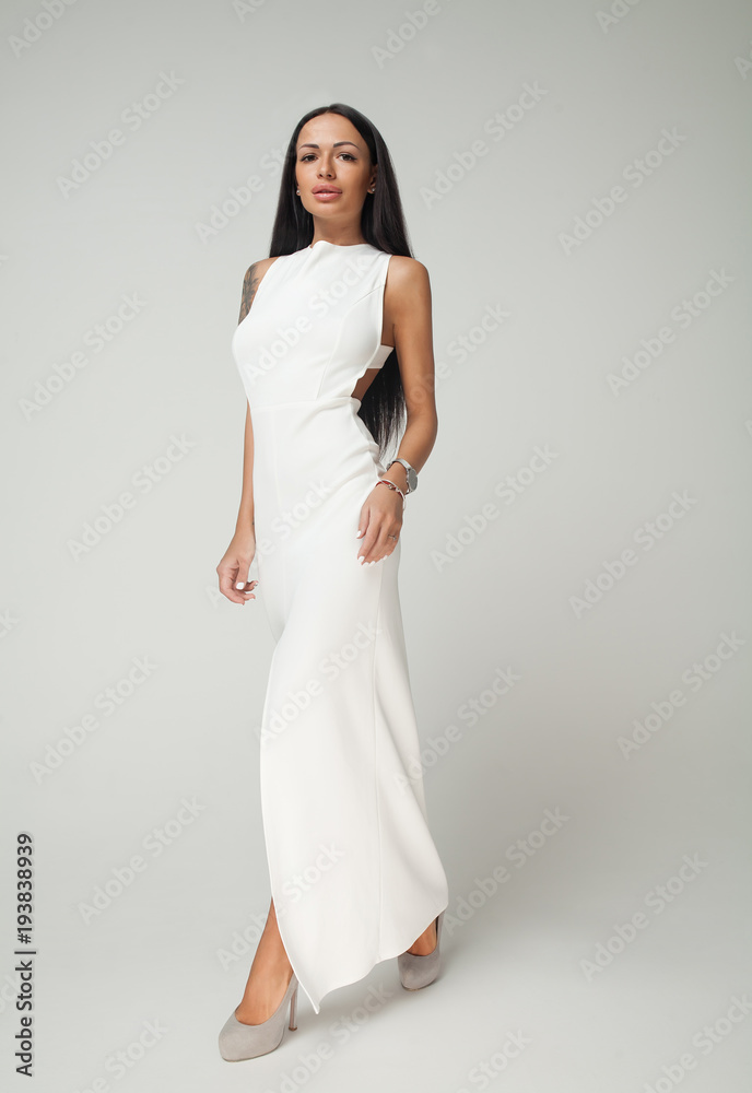 Young beautiful female model in white dress on grey background Young beautiful female model in white dress on grey background