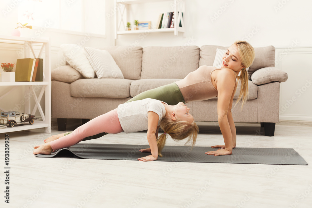 Fototapeta premium Matka i córka robi ćwiczenia jogi w domu