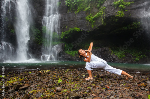 Woman practices yoga near Sekumpul waterfall in Bali  Indonesia