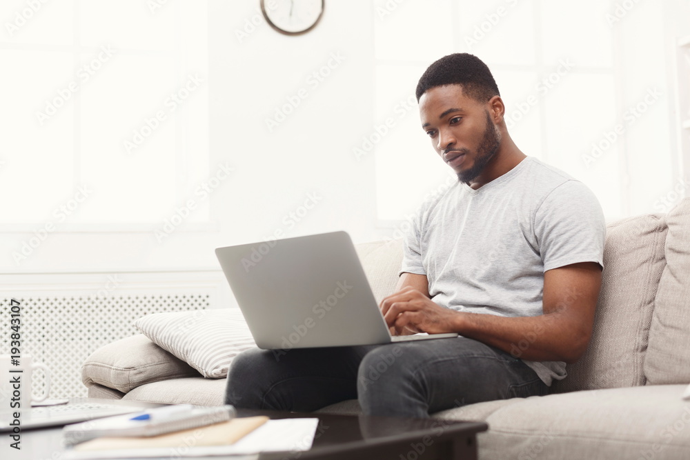 Young man at home messaging online on laptop
