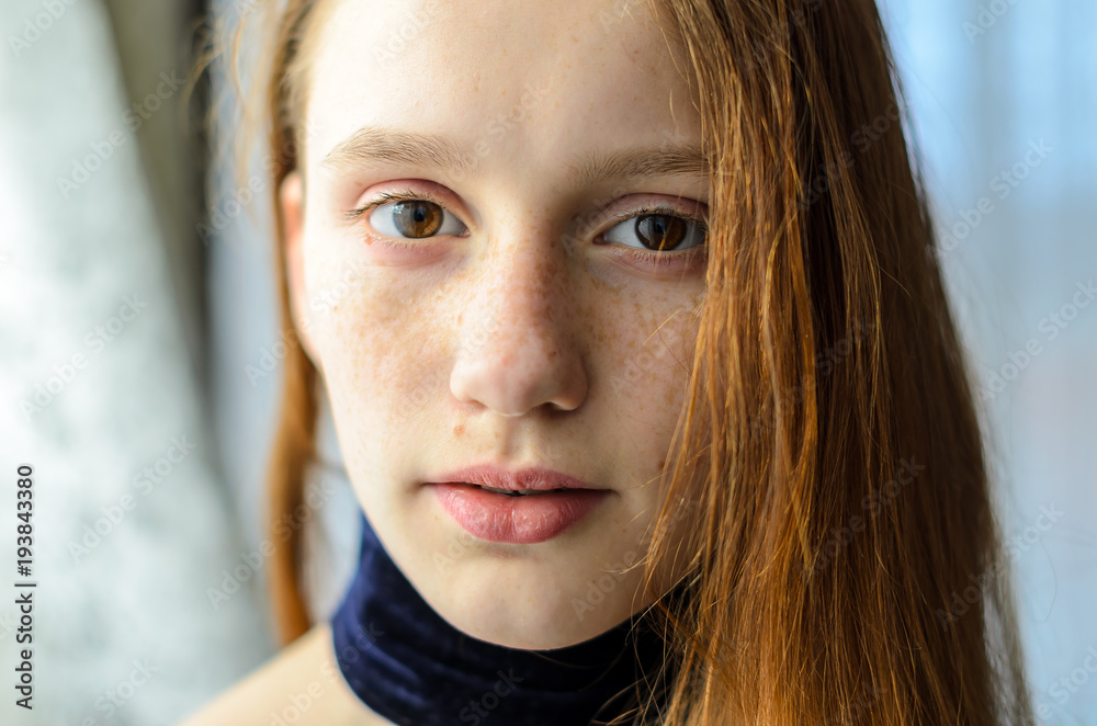 an attractive young girl with an expressive look of brown eyes with freckles on her face and red straight hair looks directly at you an attractive young girl with an expressive look of brown eyes with freckles on her face and red straight hair looks directly at you
