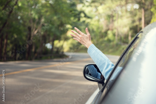 Close up woman hand with arm raised relaxing and enjoying road trip. she happy driver in car on road in nature. copy space.