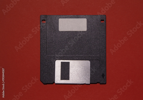 An obsolete floppy disk on a red background. You can write something on the blank label. 