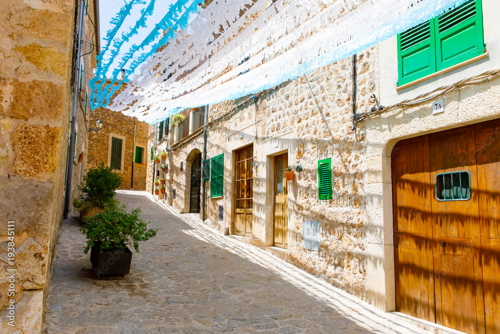 Fototapeta premium Beautiful street in Valldemossa with traditional flower decoration, famous old mediterranean village of Majorca. Balearic island Mallorca, Spain
