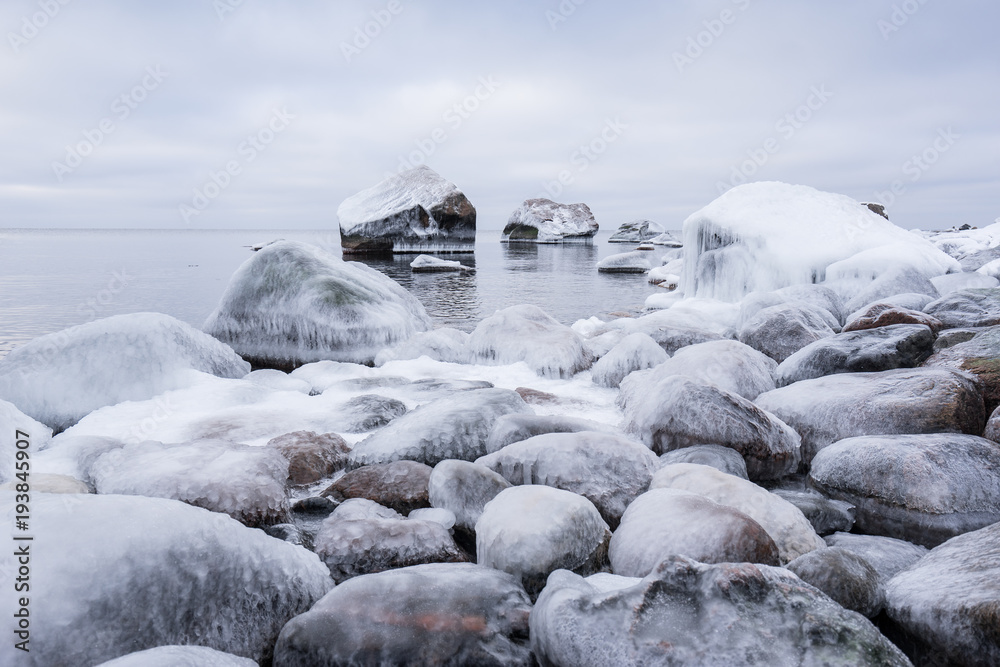 Rocky beach on wintertime. Evening light and icy weather on shore like fairy tale country. Winter on coast. Blue sky, white snow, ice covers the land on seaside. Waterside on Juminda, Estonia, Europe Rocky beach on wintertime. Evening light and icy weather on shore like fairy tale country. Winter on coast. Blue sky, white snow, ice covers the land on seaside. Waterside on Juminda, Estonia, Europe