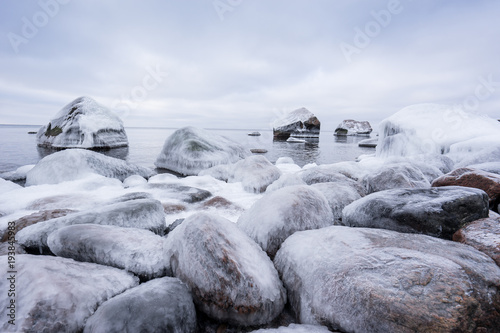 Rocky beach on wintertime. Evening light and icy weather on shore like fairy tale country. Winter on coast. Blue sky, white snow, ice covers the land on seaside. Waterside on Juminda, Estonia, Europe photo