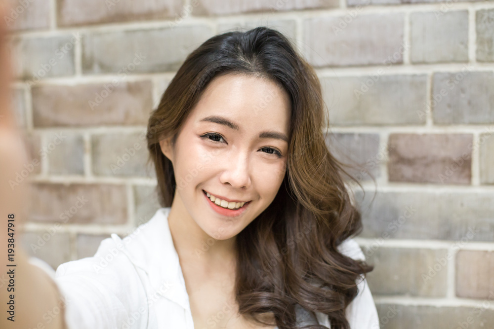 Asian woman using smartphone with smiling at wall background. Woman using smartphone for selfie or video call in social media. People with technology concept. Asian woman using smartphone with smiling at wall background. Woman using smartphone for selfie or video call in social media. People with technology concept.