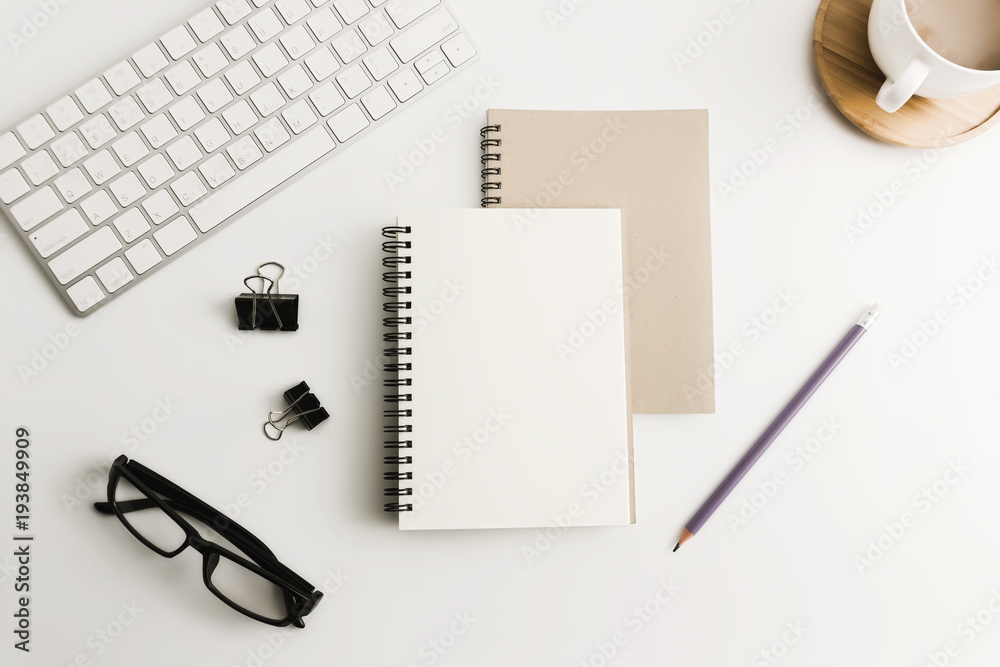 White office desk table with blank notebook, computer, supplies and coffee cup. Top view with copy space. Flat lay. White office desk table with blank notebook, computer, supplies and coffee cup. Top view with copy space. Flat lay.