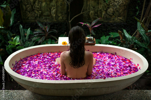 Beauty young Woman relaxing in outdoor bath with tropical flowers.Spa,organic and skin care concept.