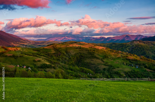 beautiful rural area in mountains. gorgeous landscape with beautiful cloud formations over the mountain ridge in red light at sunset
