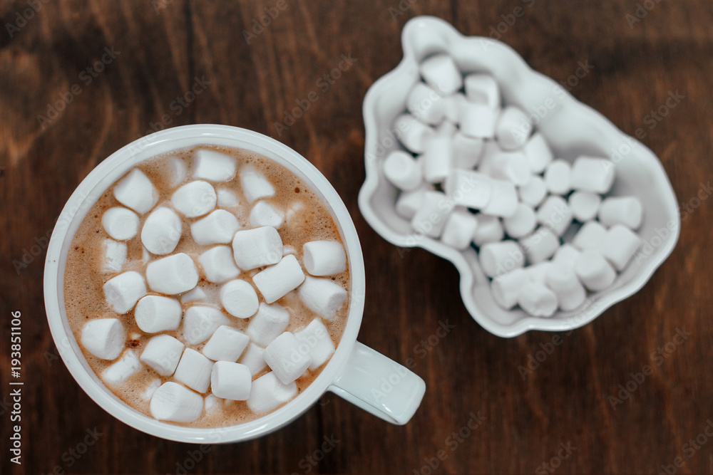 white cup with a white marshmelow on a wooden background white cup with a white marshmelow on a wooden background