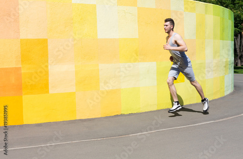 Young man running against bright wall photo