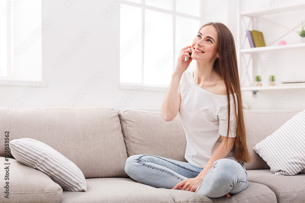 Young woman sitting on sofa and talking on cell phone Young woman sitting on sofa and talking on cell phone