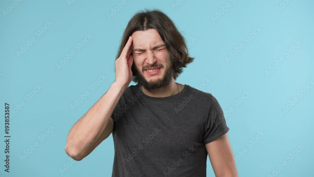 Portrait of sick or tired mature man rubbing temples because of headache suffering from migraine, isolated over blue background. Concept of emotions Portrait of sick or tired mature man rubbing temples because of headache suffering from migraine, isolated over blue background. Concept of emotions