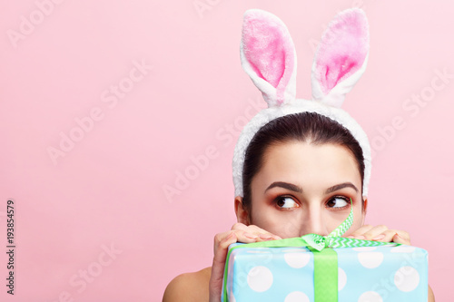 Canvas Print Happy young woman wearing bunny ears and holding present