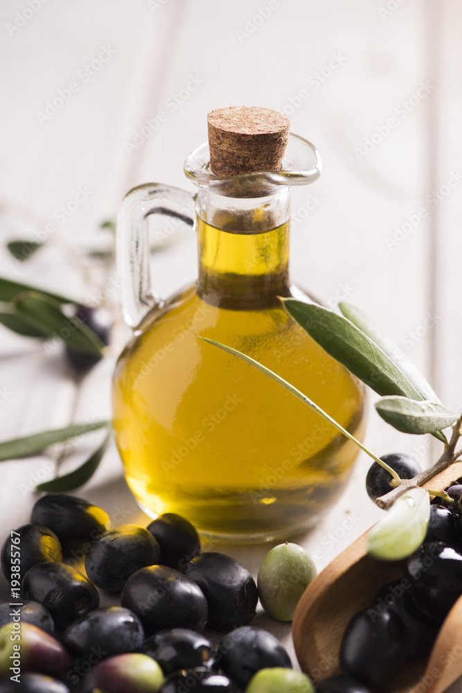 Olives and a bottle of olive oil on white dark wooden table Olives and a bottle of olive oil on white dark wooden table