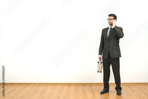 The man with a case phones on the white wall background