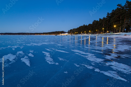 lake and beach during the sunset with ice and snow on the ice