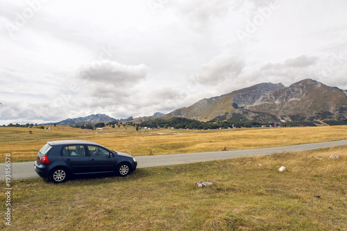car with the traveler stands on the roadside in a yellow field in zabljak in Montenegro in autumn © saulich84