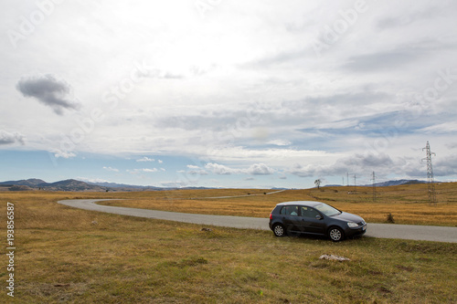 car with the traveler stands on the roadside in a yellow field in zabljak in Montenegro in autumn