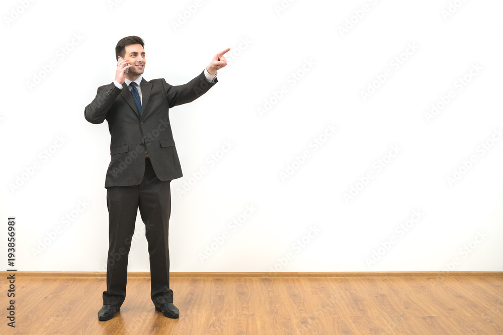 The businessman phones and gestures on the white wall background The businessman phones and gestures on the white wall background