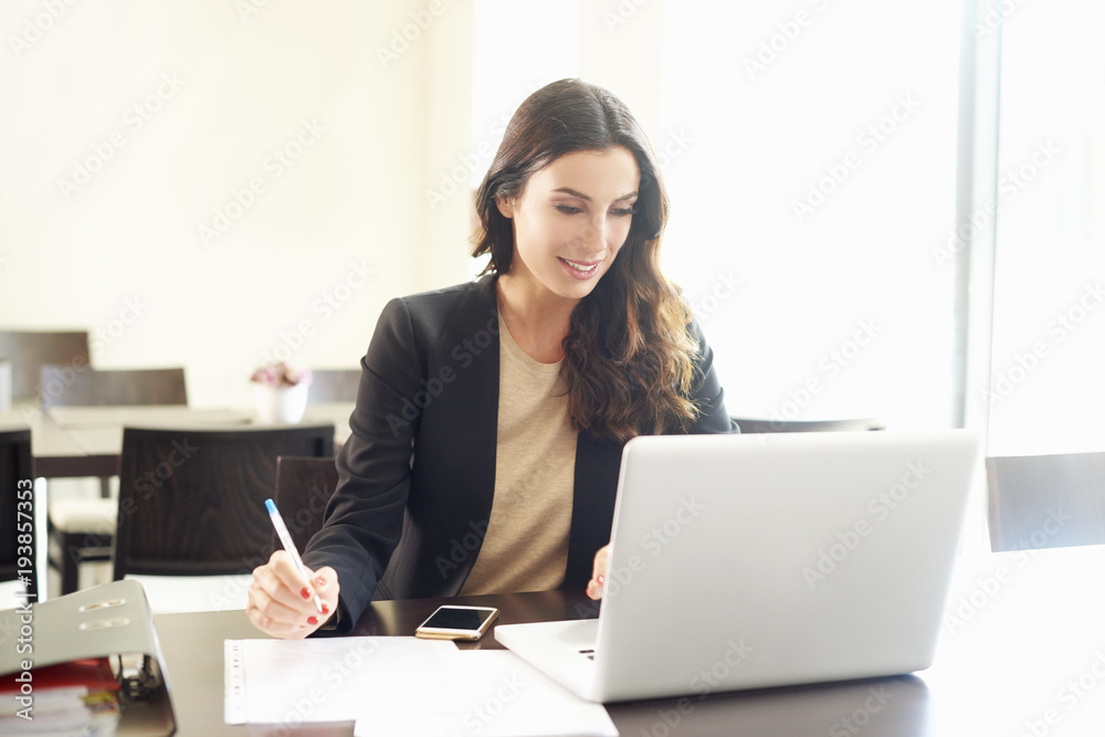 Thinking young businesswoman in the office.Shot of a beautiful young business woman sitting at office desk and using laptop while working. Thinking young businesswoman in the office.Shot of a beautiful young business woman sitting at office desk and using laptop while working.