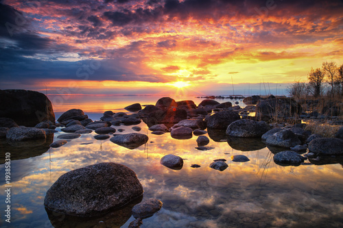 colorful sunset by a lake with a rocky beach