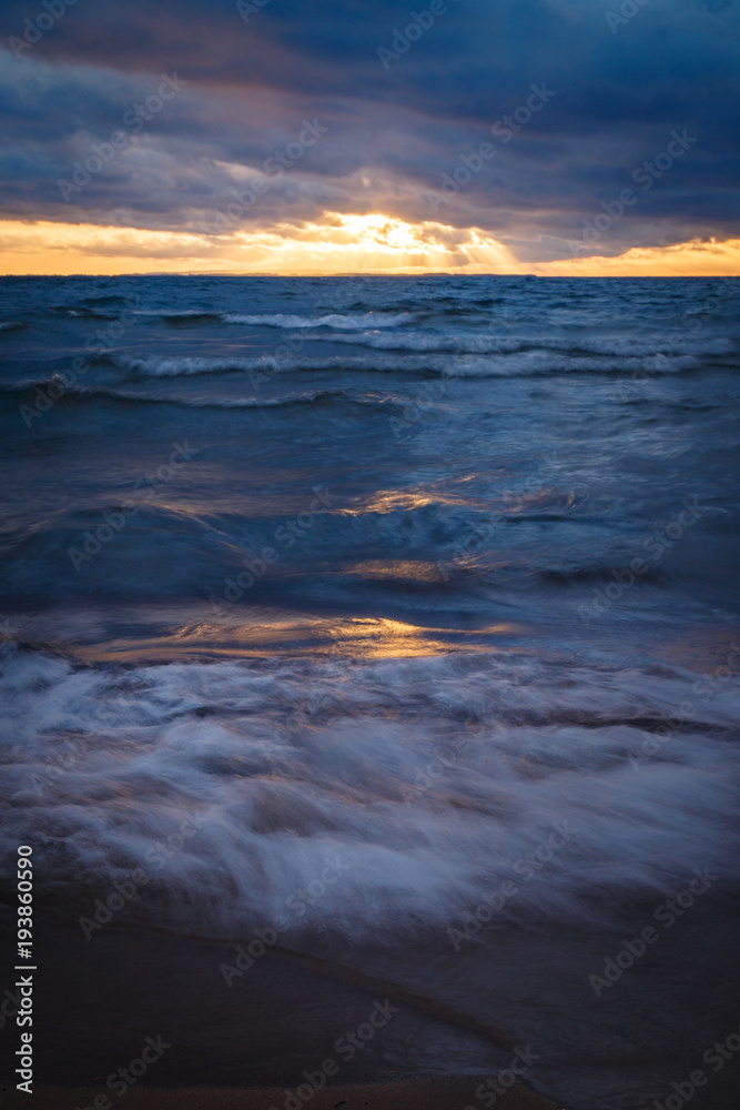 waves rushing onto a sandy beach at sunset waves rushing onto a sandy beach at sunset