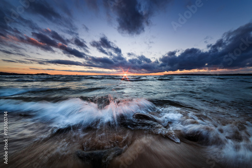 waves rushing onto a sandy beach at sunset