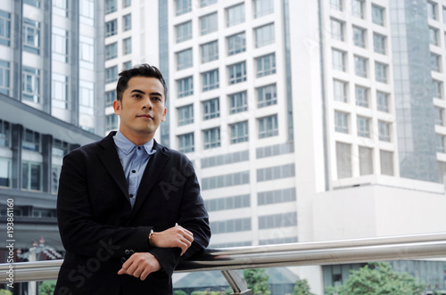 young handsome asian business man wearing modern black suit standing looking into camera in building city background, confident, team leader, successful, manager, portrait and entrepreneurship concept