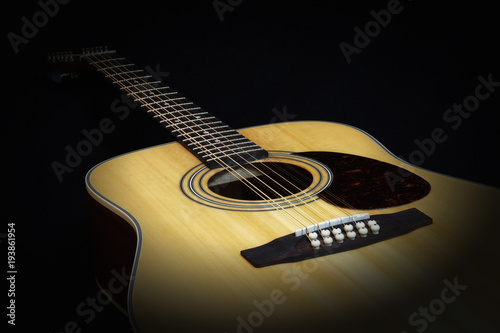Classic acoustic twelve strings guitar sunburst color top from spruce with cutaway fragment isolated on black background side view closeup