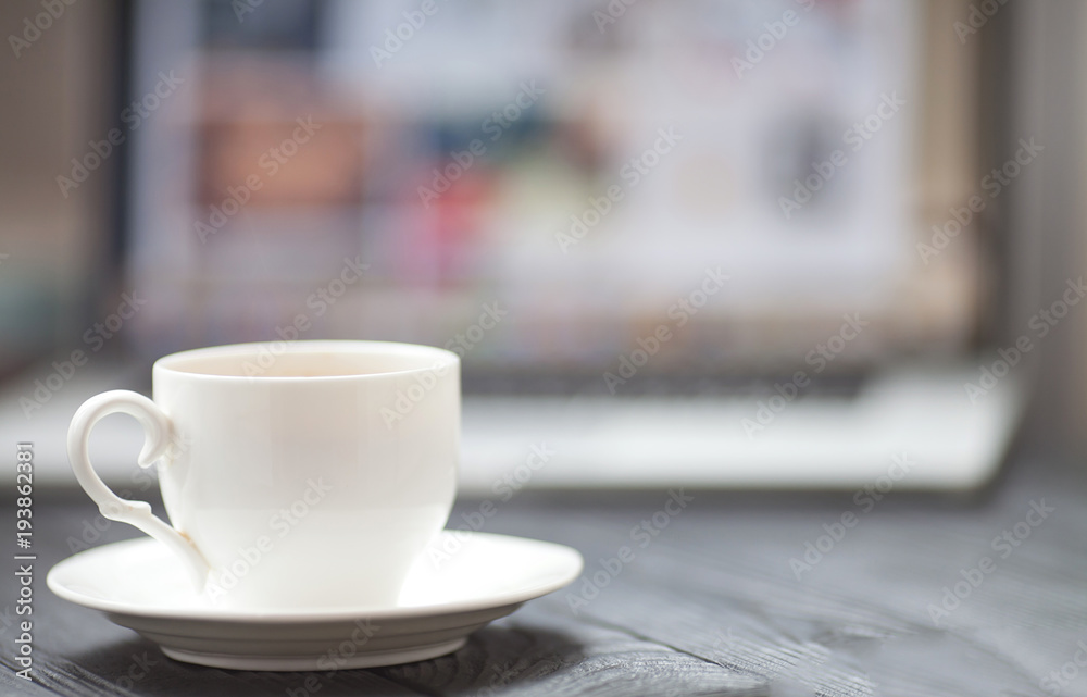Coffee Cup on the white table on blurred laptop background for Business Concept. Coffee Cup on the white table on blurred laptop background for Business Concept.