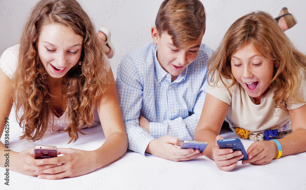 Game addiction concept. Group of friends smiling and gaming on smart phones and mobile devices. Game addiction concept. Group of friends smiling and gaming on smart phones and mobile devices.