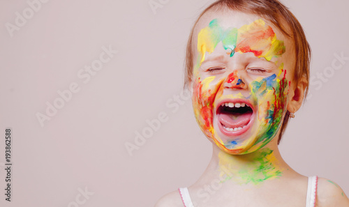 Fototapeta Naklejka Na Ścianę i Meble -  Beauty concept. Children's art makeup. Funny portrait of laughed little beautiful children girl with colored face.