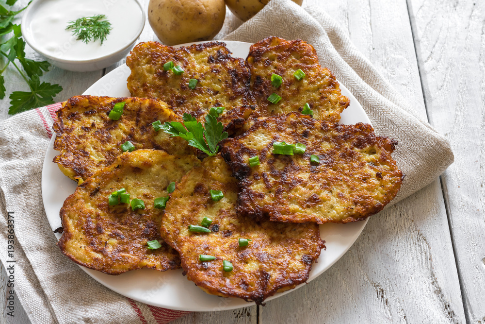 homemade potato pancakes with sour cream on rustic wooden table homemade potato pancakes with sour cream on rustic wooden table