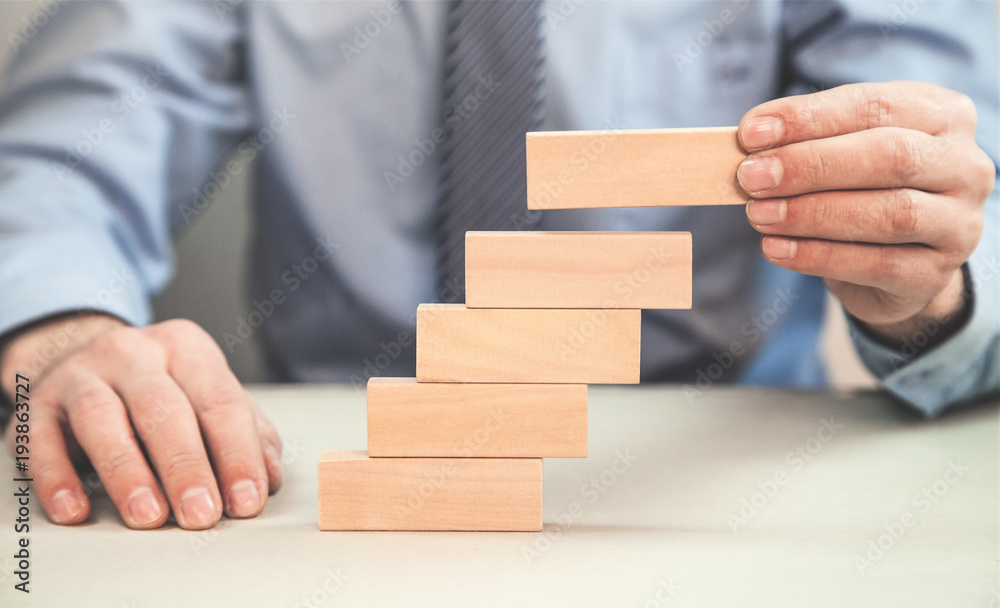 Man stacking wooden blocks. Development concept.