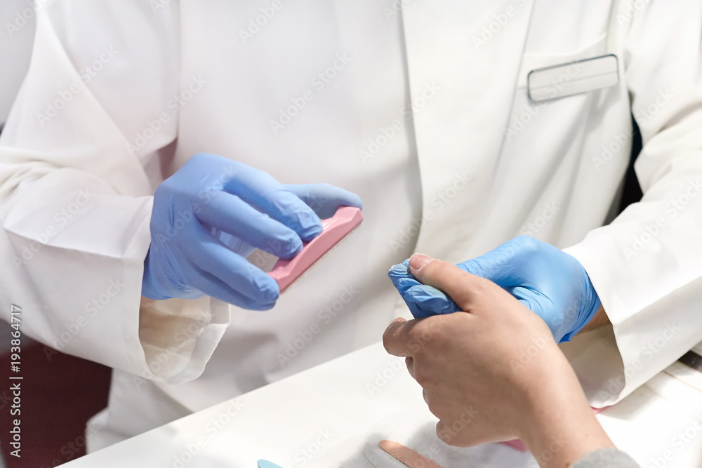 Closeup of a nail technician gives the client a manicure in a manicure. Closeup of a nail technician gives the client a manicure in a manicure.