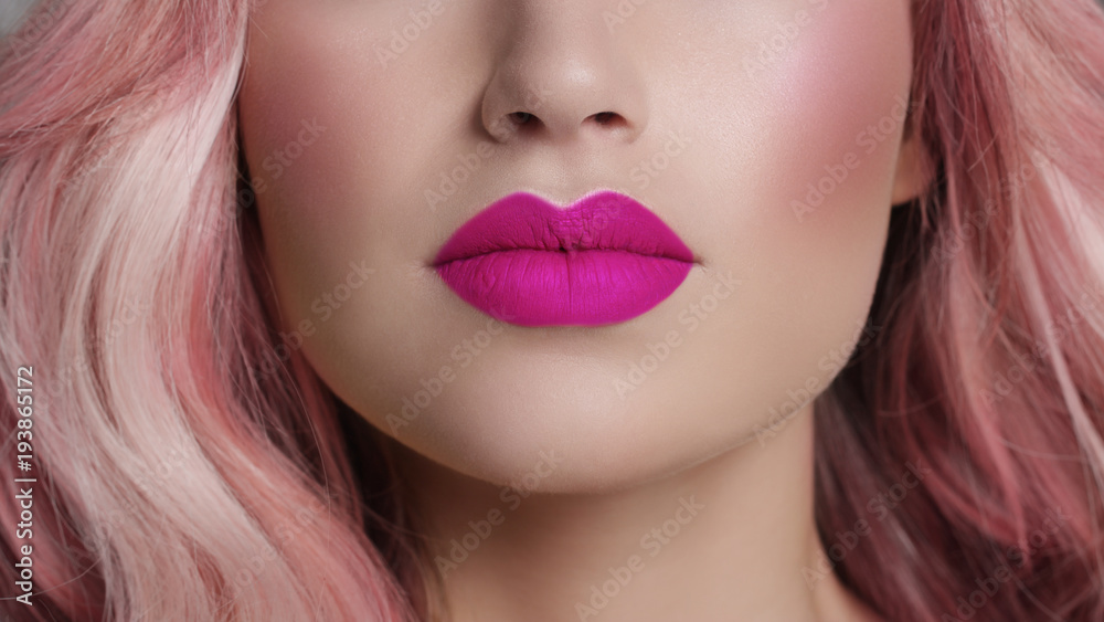 Foto Stock Close-up of woman's lips with fashion bright pink make-up.  Beautiful female mouth, full lips with perfect makeup. Part of female face.  Choice lipstick. Pink wavy hair of a Barbie doll