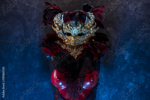 Venetian red, mask and red corset with pieces of gold and black lace fabrics on metal breastplate. handmade piea for parties or costume meetings photo