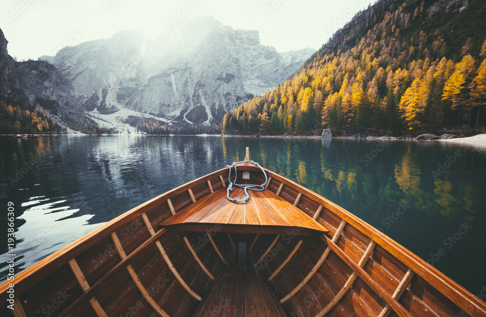 Wooden rowing boat on a lake in the Dolomites in fall - obrazy, fototapety, plakaty 