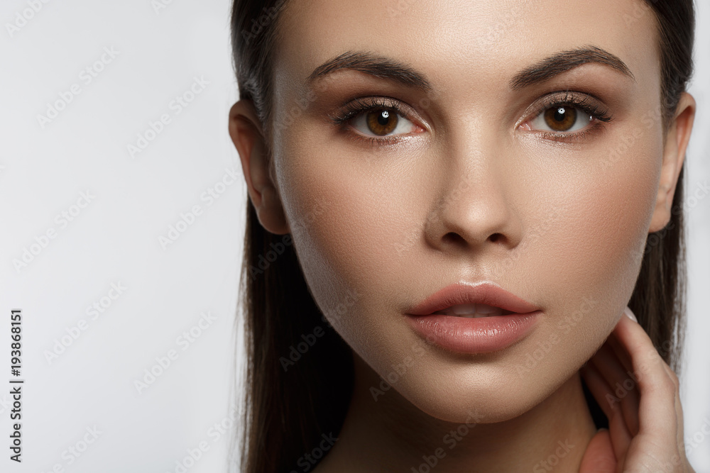 Close up portrait of sensual girl enjoying skin care treatment. She is touching face while looking at camera with passion. Isolated and copy space