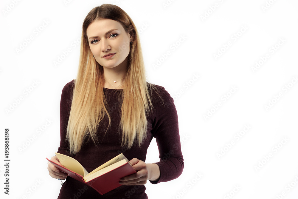 Young charming girl in sweater holding book and tablet and smiling at camera. Young charming girl in sweater holding book and tablet and smiling at camera.
