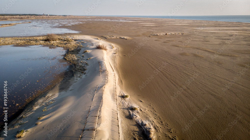 vol au dessus d'une dune qui sépare un étang et la plage avec la mer au fond