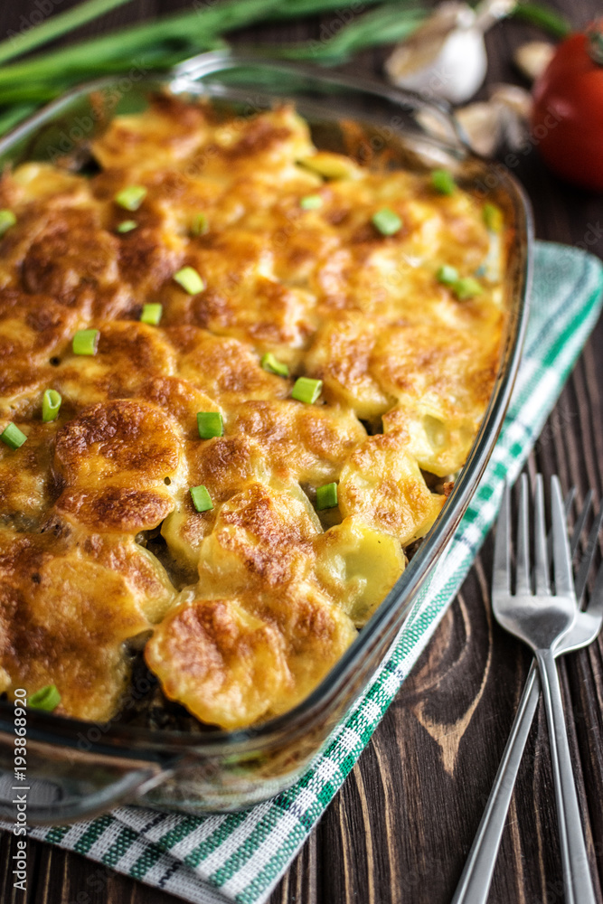 Potato casserole with meat and mushrooms on a wooden background Potato casserole with meat and mushrooms on a wooden background