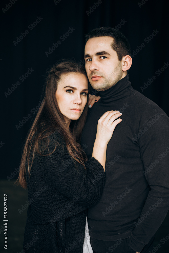 Portrait of a beautiful couple who stands on a black background and looks at the camera Portrait of a beautiful couple who stands on a black background and looks at the camera