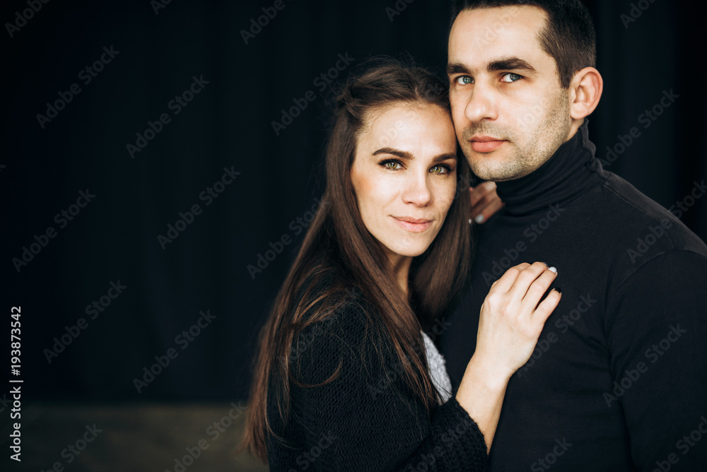 Portrait of a happy smiling couple who stands on a black background and looks at the camera Portrait of a happy smiling couple who stands on a black background and looks at the camera
