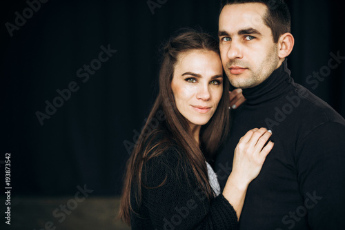 Portrait of a happy smiling couple who stands on a black background and looks at the camera